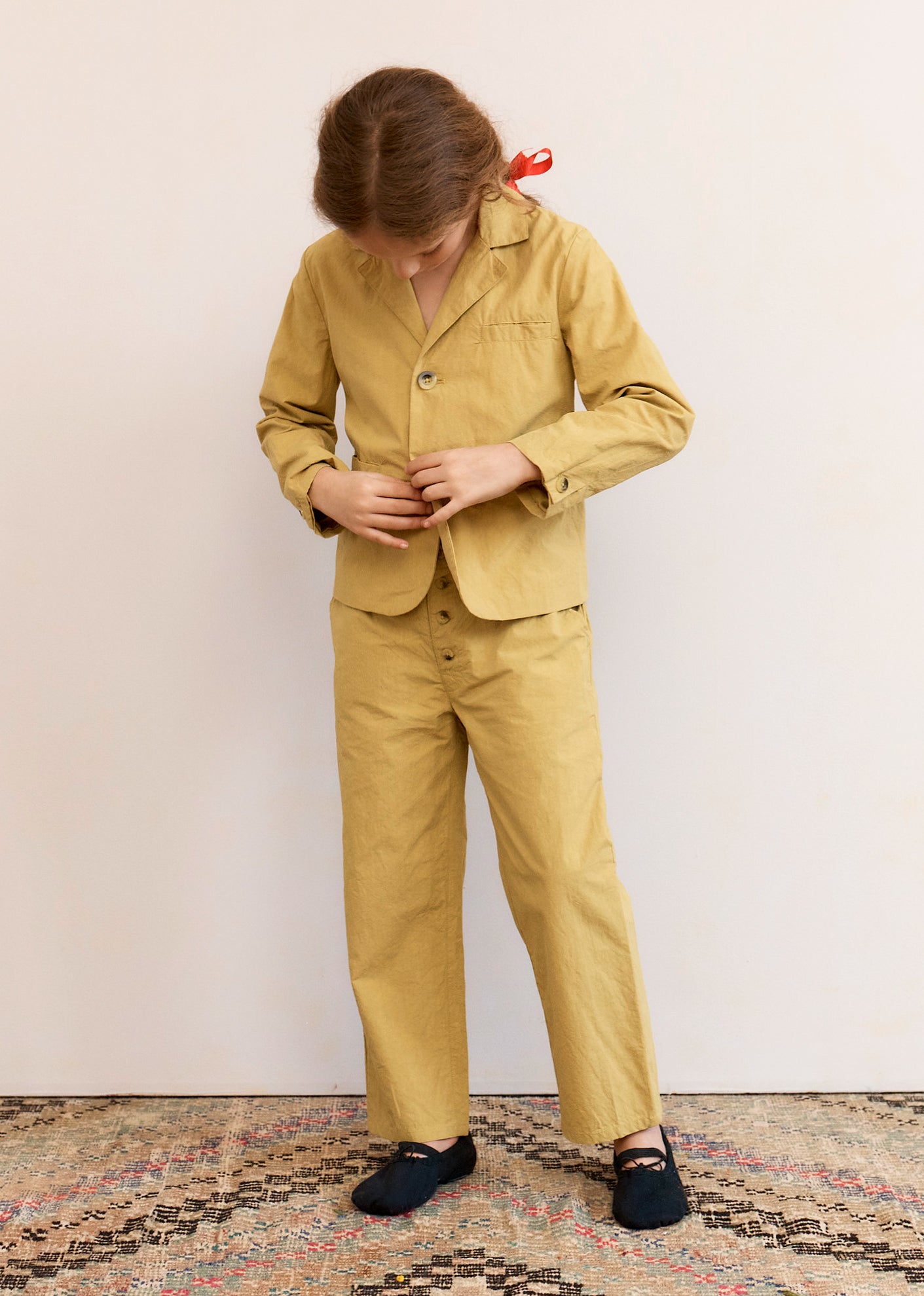Person wearing a mustard yellow suit standing against a plain background